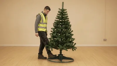 Man Adjusting The Base Of An Artificial Christmas Tree