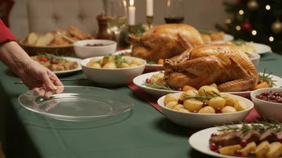 Person Placing Empty Plate On Festive Christmas Dinner Table