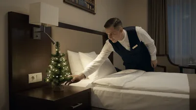 Hotel Staff Member Adjusting Bedding in Guest Room