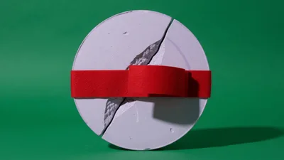 Red Ribbon Wrapping Around A Cracked Concrete Disc