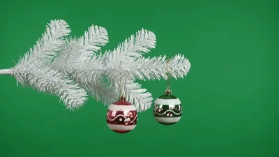 Two Christmas Ornaments Hanging From A White Pine Branch