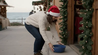 Woman Placing Water Bowl Outside Christmas Market Stall