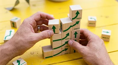 Hands Building A Business Growth Pyramid With Wooden Blocks