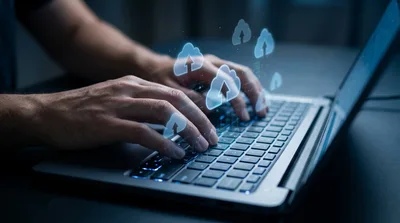 Person Typing on Laptop with Digital Cloud Upload Icons