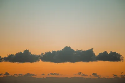Dark Clouds Against A Vibrant Orange Sunset Sky