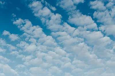 White Fluffy Clouds Scattered Across A Bright Blue Sky