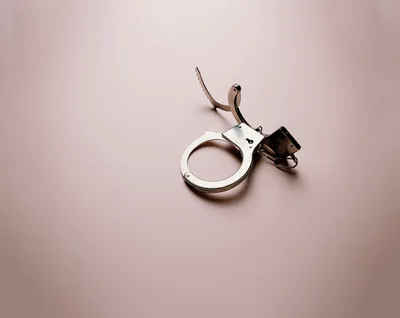 Open Metal Handcuffs Isolated On A Soft Pink Background