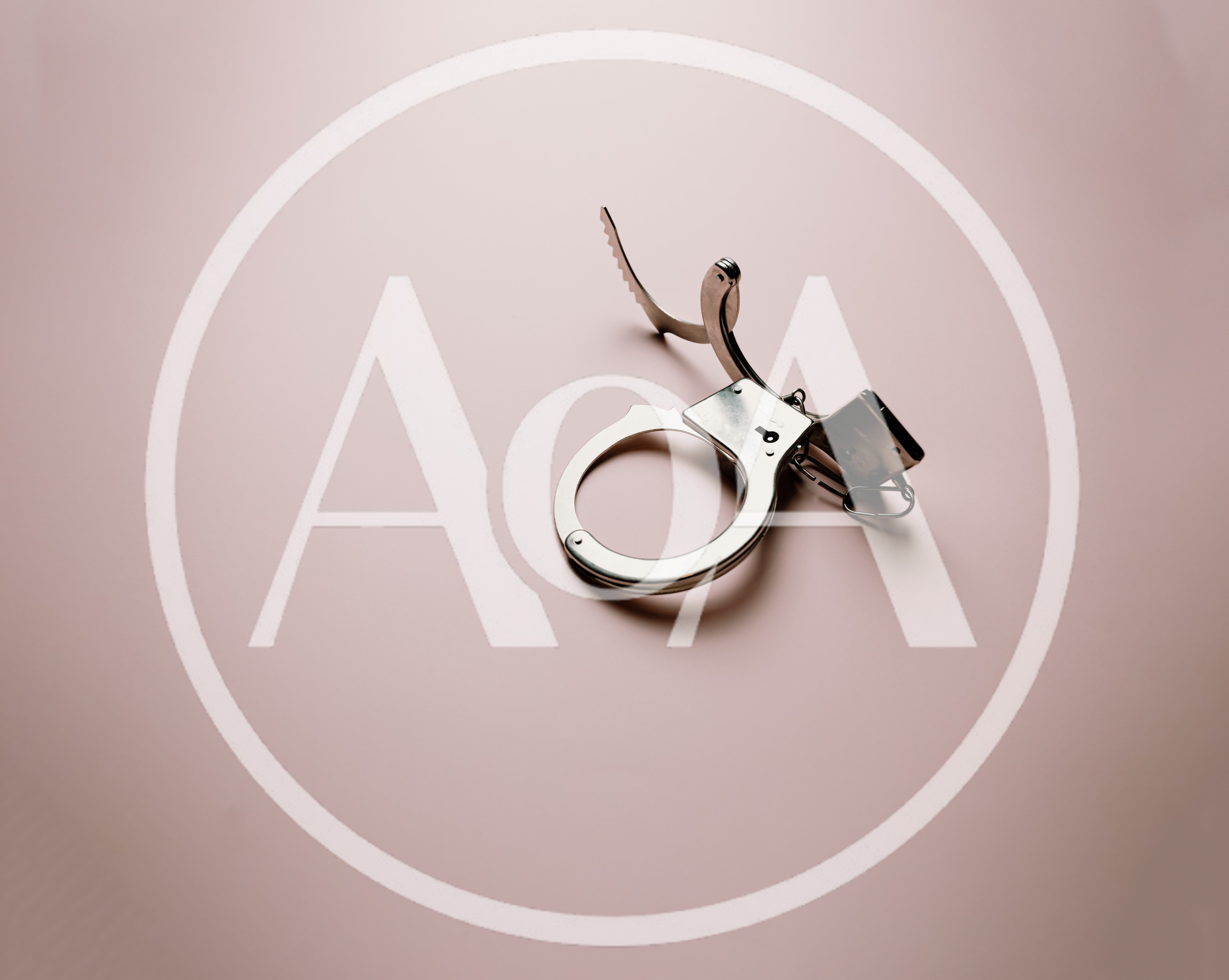 Open Metal Handcuffs Isolated On A Soft Pink Background