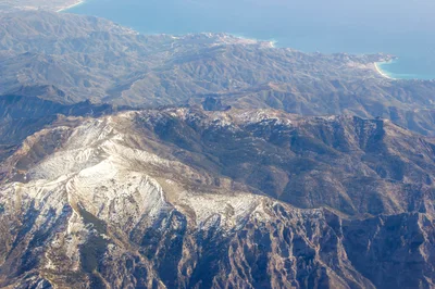 Aerial View Of Snow Capped Mountains Near Coastline