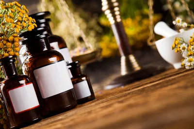 Apothecary Bottles With Herbs And Mortar On Wooden Table