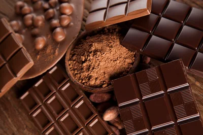 Assorted Chocolate Bars And Cocoa Powder On Wooden Table