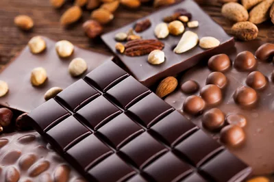 Assorted Chocolate Bars With Nuts On Wooden Background