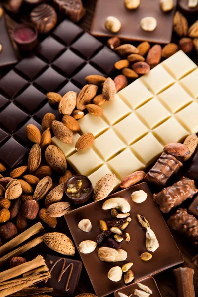 Assorted Chocolate Bars and Nuts on Wooden Background