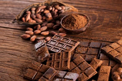 Dark Chocolate Bars and Cocoa Beans on Wooden Table