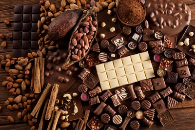 Assorted Chocolate Bars And Cocoa Ingredients On Wooden Table