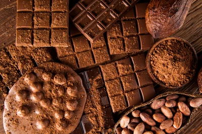 Assorted Chocolate Bars and Cocoa Beans on Wooden Table