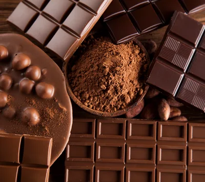 Assorted Chocolate Bars and Cocoa Powder on Wooden Table