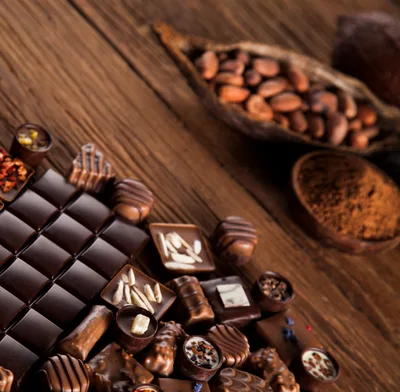 Assorted Gourmet Chocolates and Cocoa Beans on Wood
