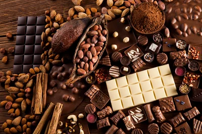 Assorted Chocolate Bars and Cocoa Beans on Wooden Table