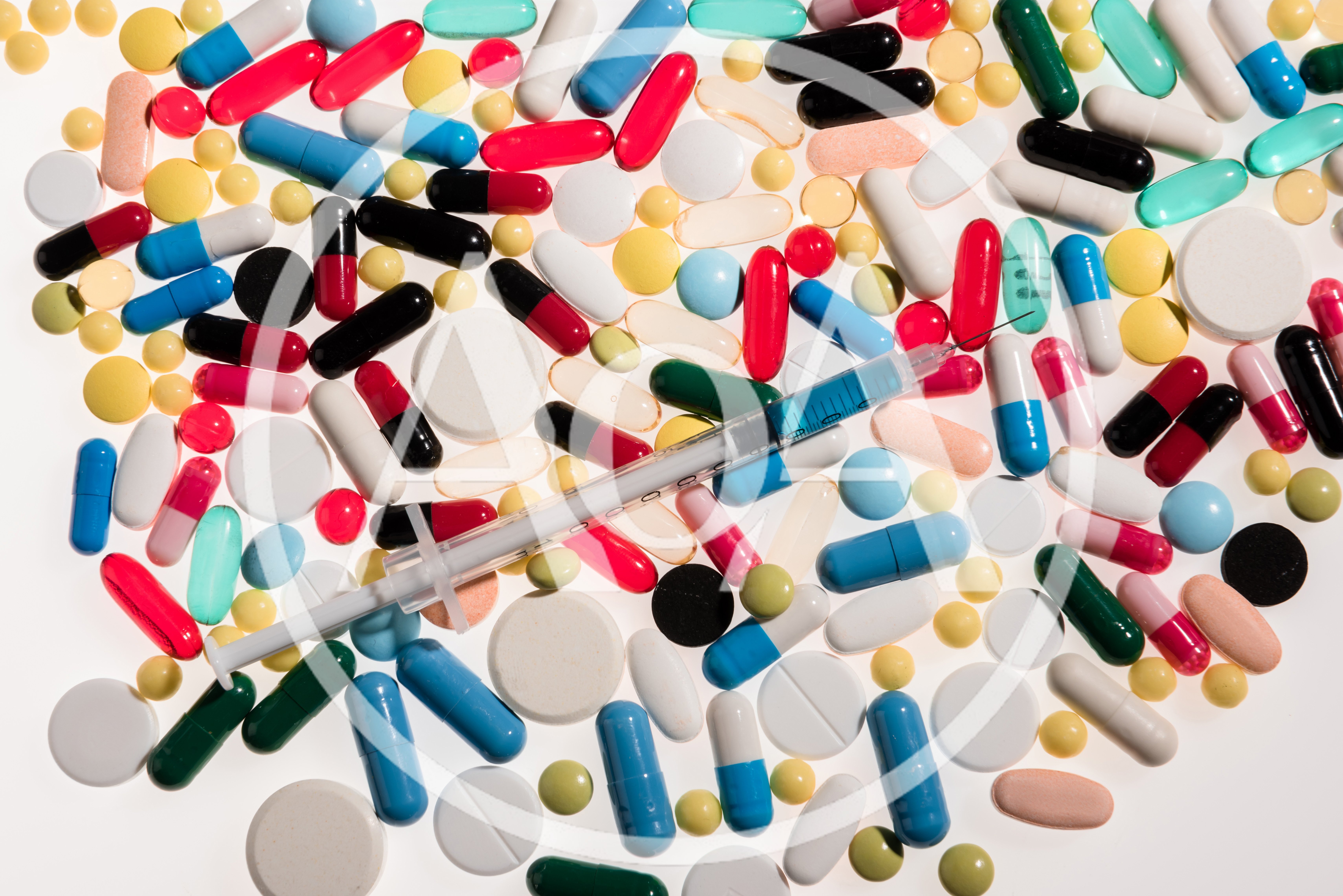 Assorted Pharmaceutical Pills and Syringe on White Background