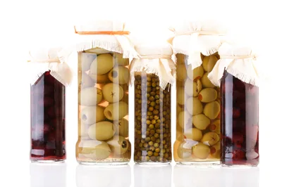 Five Glass Jars Filled With Pickled Vegetables And Fruits