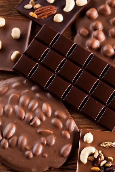 Assorted Chocolate Bars With Nuts On Wooden Background