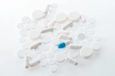 Assorted White Pills and Capsules on White Background