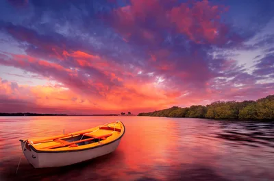 Small Orange Rowboat Floating on Calm Water at Sunset