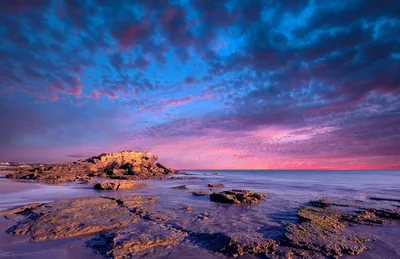 Rocky Beach Shoreline at Sunset with Vibrant Clouds