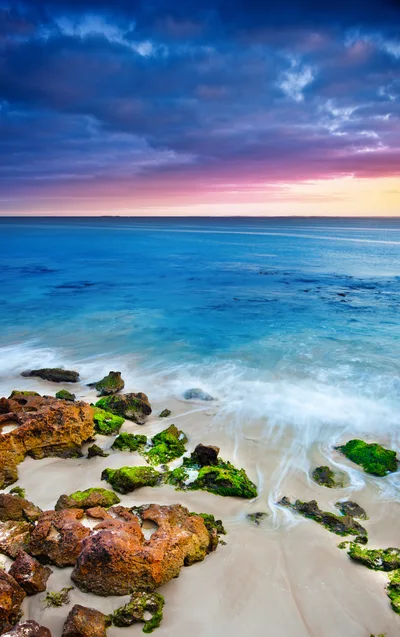 Mossy Rocks On A Sandy Beach At Sunset