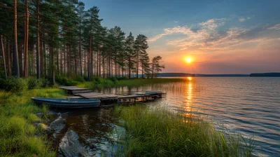 Wooden Pier And Rowboat On A Calm Lake At Sunset
