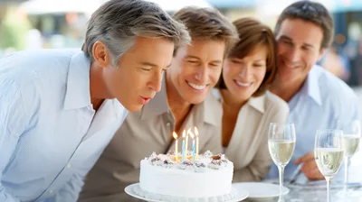Mature Friends Celebrating Birthday With Cake And Champagne