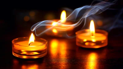 Three Lit Tea Light Candles With Wisps Of Smoke