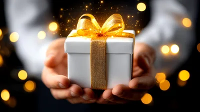 Person Holding A White Gift Box With Gold Ribbon