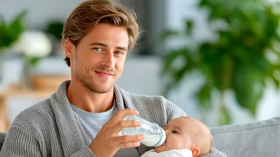 Young Father Feeding Baby With Milk Bottle
