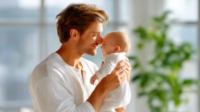 Father Holding His Newborn Baby In A Bright Room