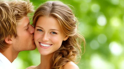 Young Man Kissing Woman On The Cheek Outdoors