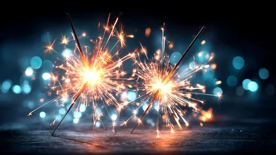 Two Burning Sparklers Against A Dark Bokeh Background