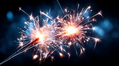 Two Burning Sparklers Against A Dark Blue Background