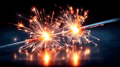 Two Burning Sparklers Against A Dark Background