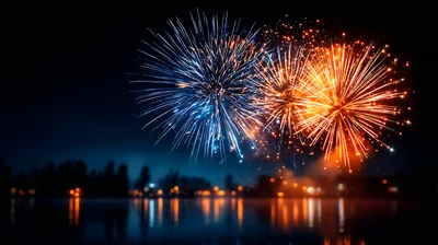 Vibrant Fireworks Display Over A Calm Lake At Night