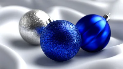 Three Decorative Christmas Ornaments On White Fabric