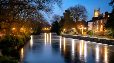 Reflective River Scene At Twilight In A Historic Town