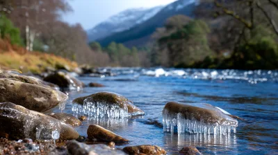 Icy Rocks Along A Flowing River In Winter