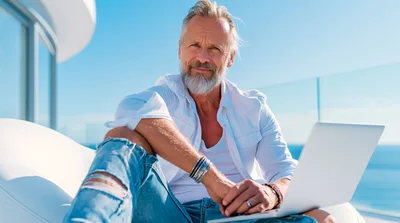 Mature Man Working On Laptop On Sunny Balcony