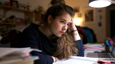 Young Woman Studying Late At Night Under Desk Lamp