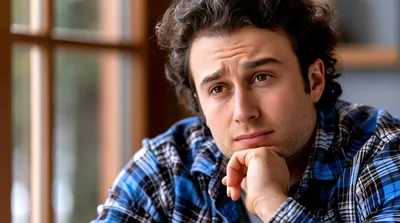 Pensive Young Man Resting Chin On Hand