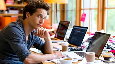 Young Man Working On Multiple Laptops In Home Office