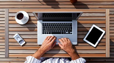 Person Working On Laptop At Wooden Table