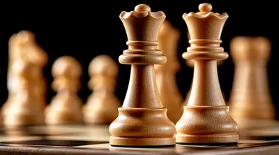 Two Wooden Chess Queens Standing On A Chessboard